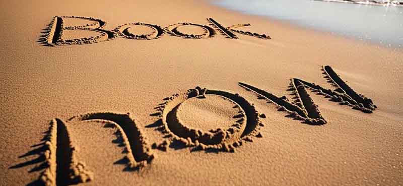 The words "Book Now" are written in the sand on a sunlit beach with the ocean visible in the background, inviting viewers to book their Dubai yacht holiday