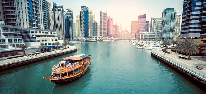 Traditional wooden dhow cruise sailing through Dubai Marina during the winter season, surrounded by modern skyscrapers